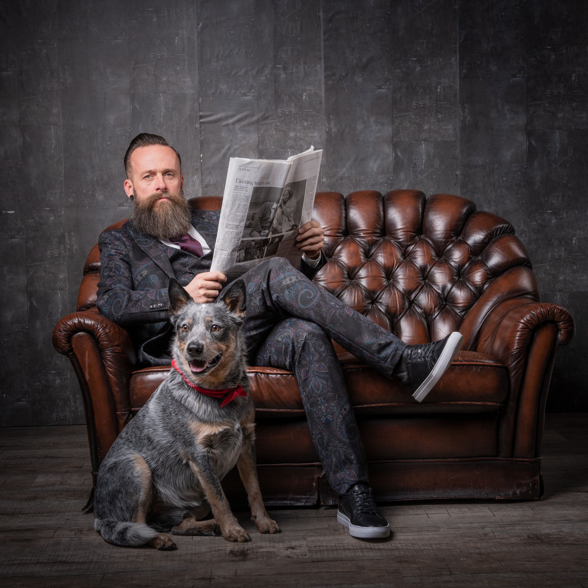 Mann mit Bart auf einem Ledersofa, daneben sein Hund