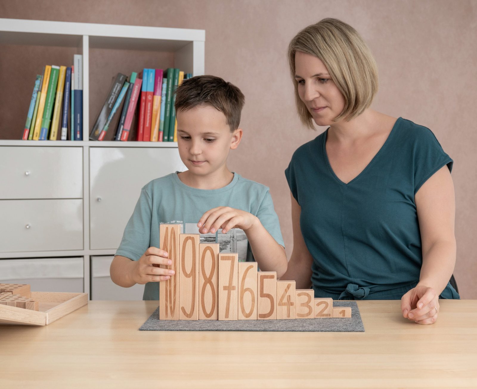Ein Bub baut mit Andrea Karner eine Zahlentreppe aus Holz von 1 bis 10